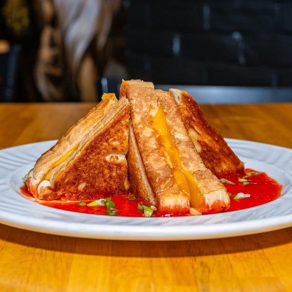 Lost Lion's grilled cheese sandwich, cut into triangles, served with red dipping sauce and green onions.