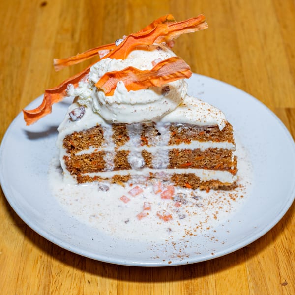 Lost Lion's carrot cake slice with cream cheese frosting, ice cream, and candied carrot strips.